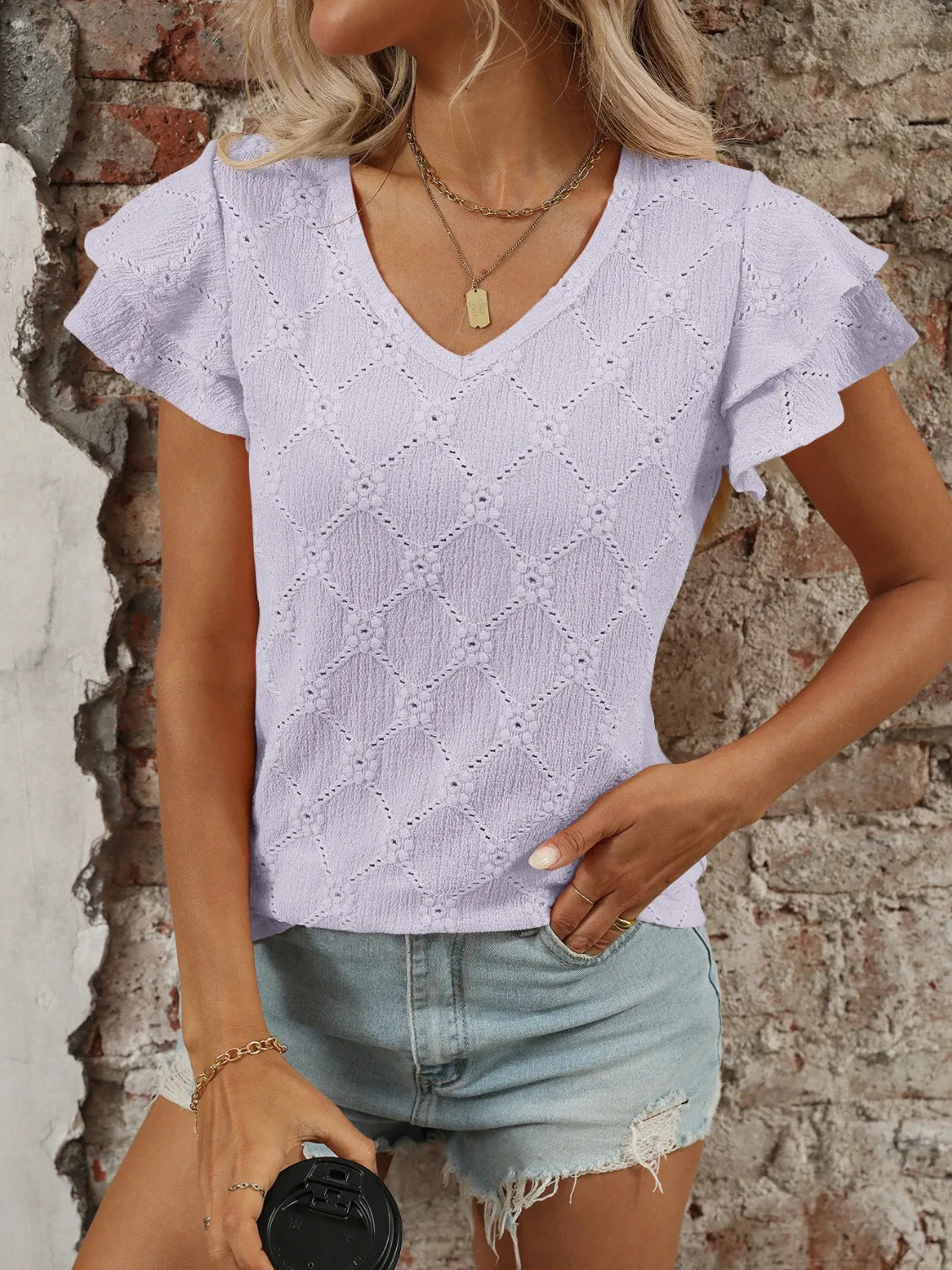 Eyelet V-neck ruffled cap sleeve top with decorative buttons and lace.