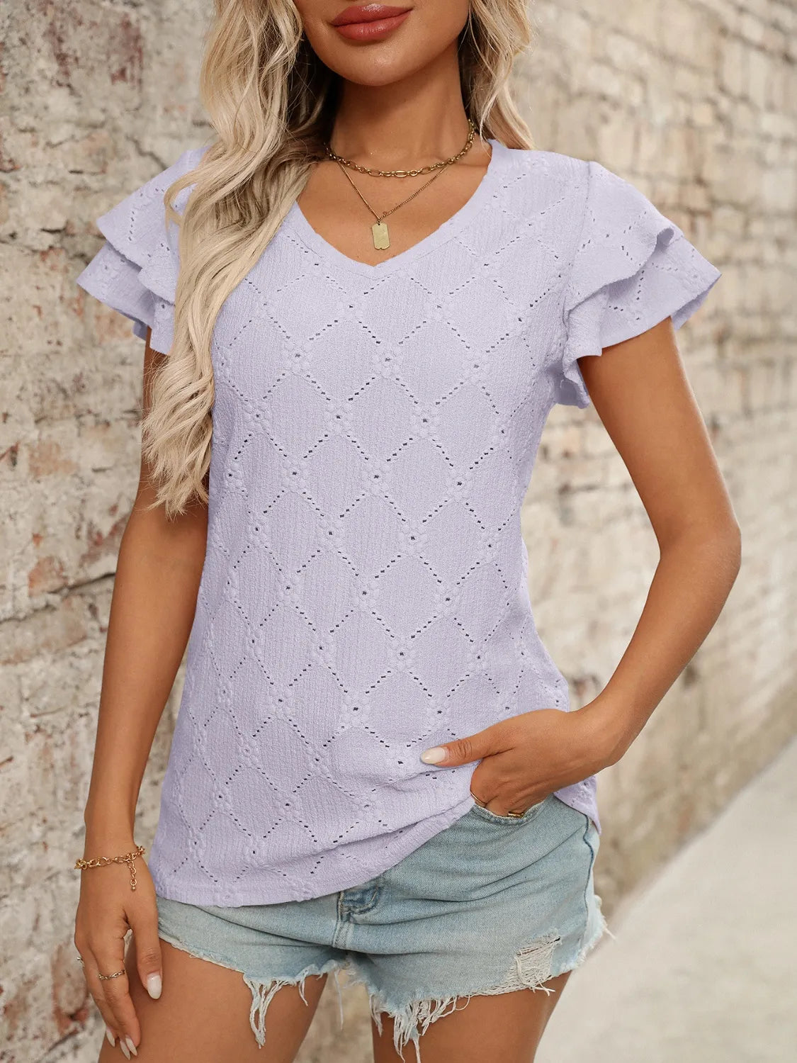Eyelet V-neck ruffled cap sleeve top with decorative buttons and lace.