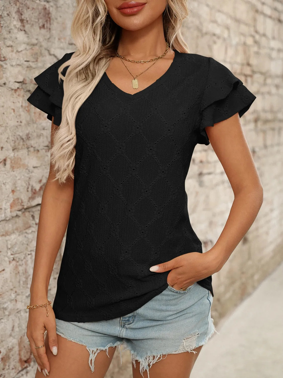 Eyelet V-neck ruffled cap sleeve top with decorative buttons and lace.