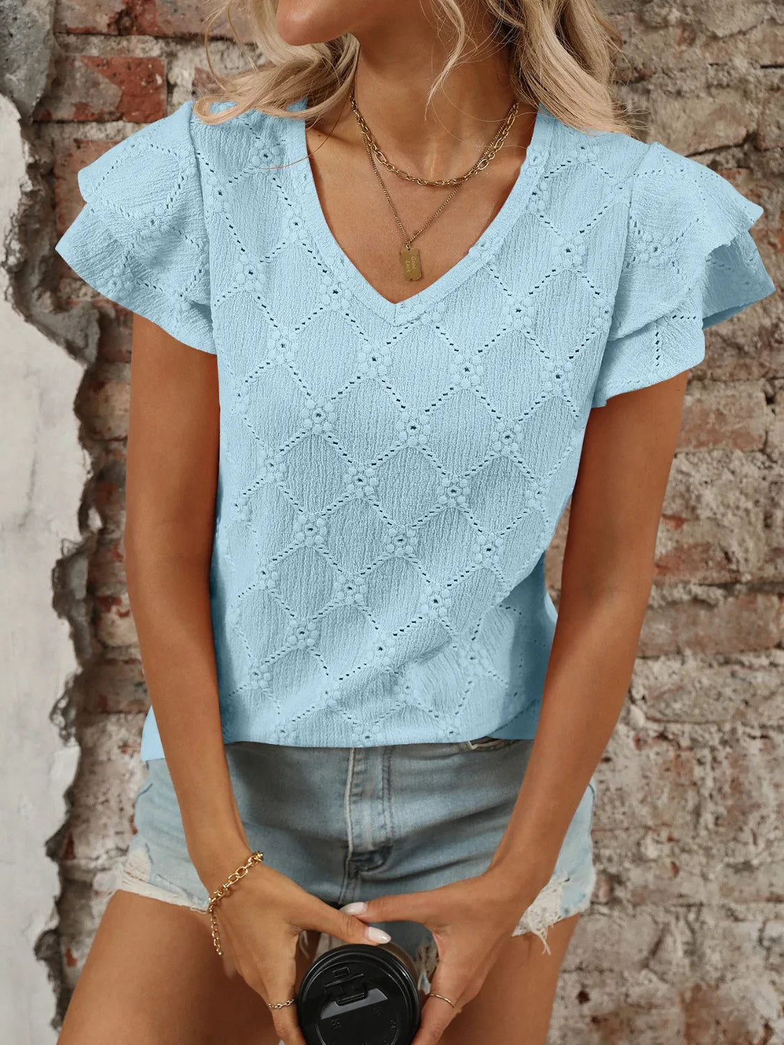 Eyelet V-neck ruffled cap sleeve top with decorative buttons and lace.