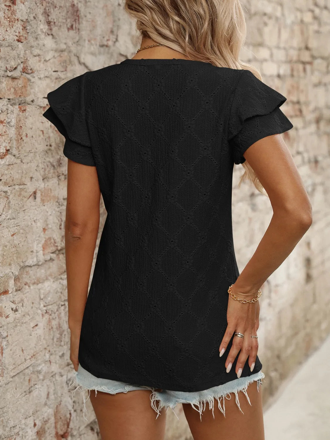 Eyelet V-neck ruffled cap sleeve top with decorative buttons and lace.