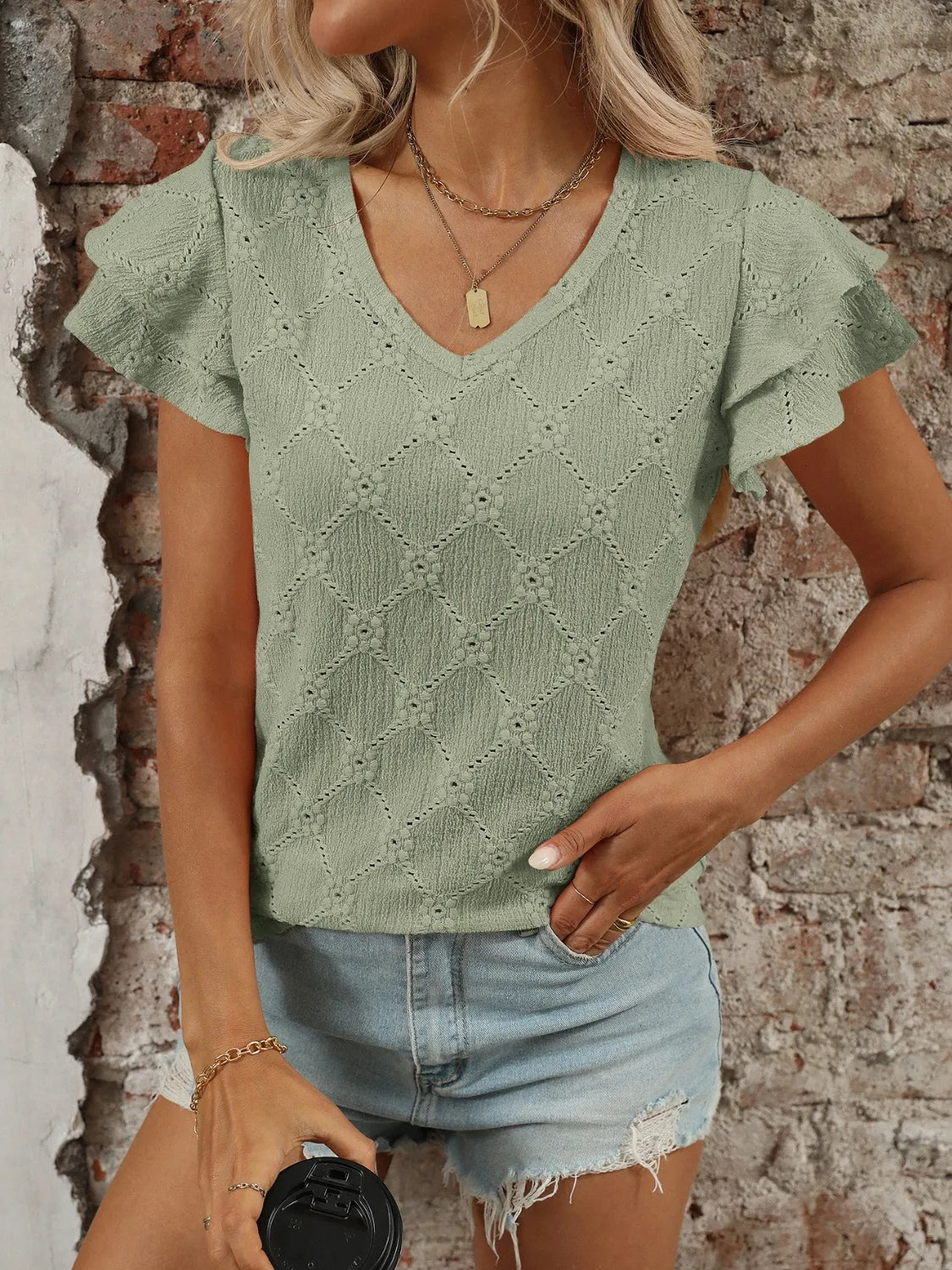 Eyelet V-neck ruffled cap sleeve top with decorative buttons and lace.