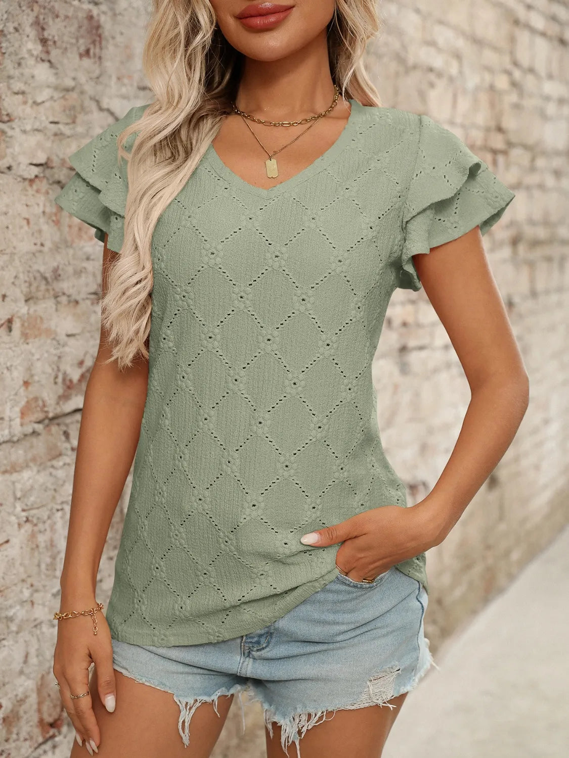 Eyelet V-neck ruffled cap sleeve top with decorative buttons and lace.