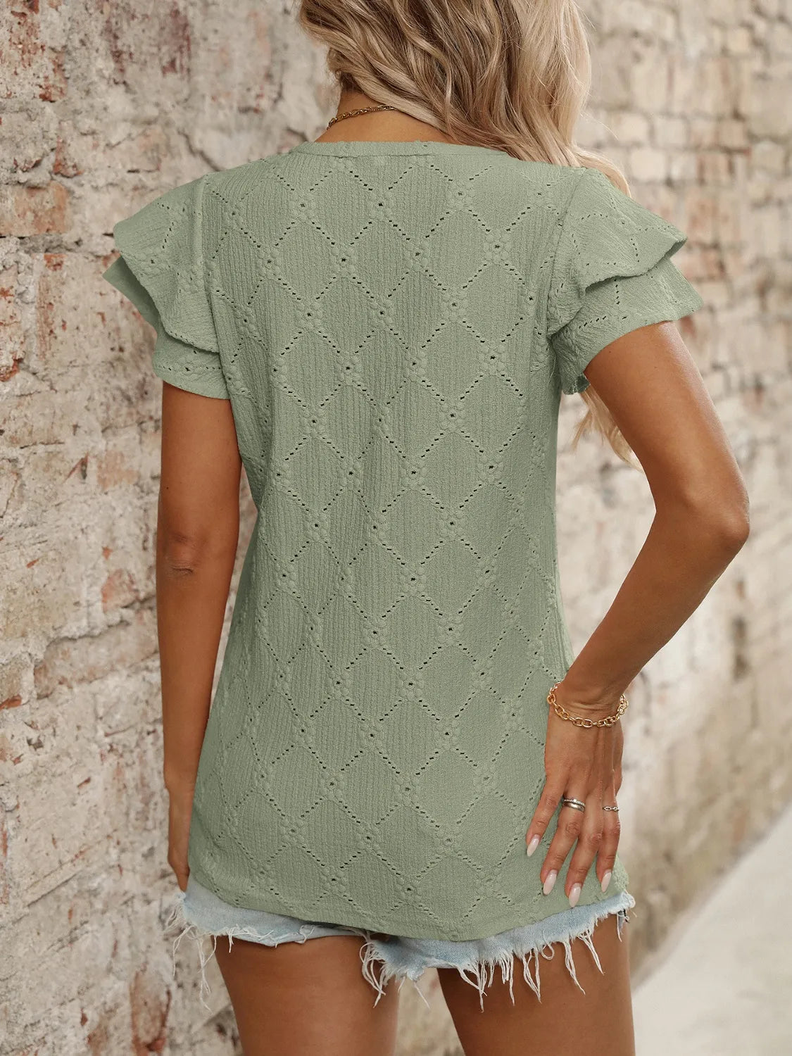 Eyelet V-neck ruffled cap sleeve top with decorative buttons and lace.