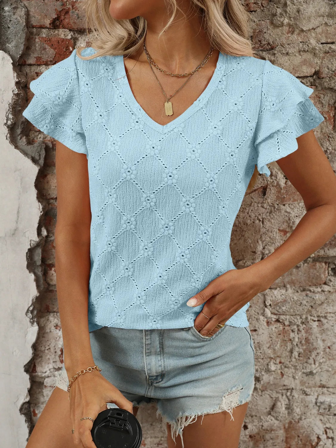 Eyelet V-neck ruffled cap sleeve top with decorative buttons and lace.