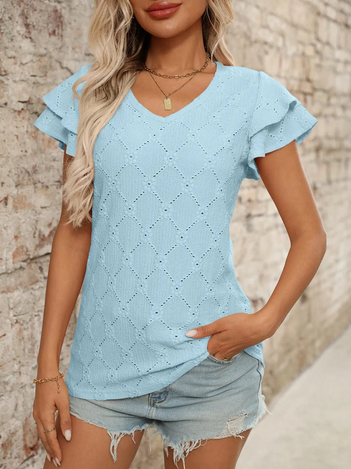 Eyelet V-neck ruffled cap sleeve top with decorative buttons and lace.