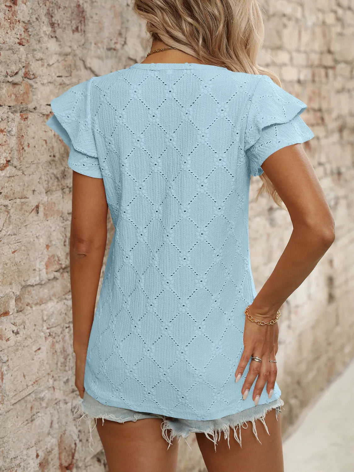 Eyelet V-neck ruffled cap sleeve top with decorative buttons and lace.