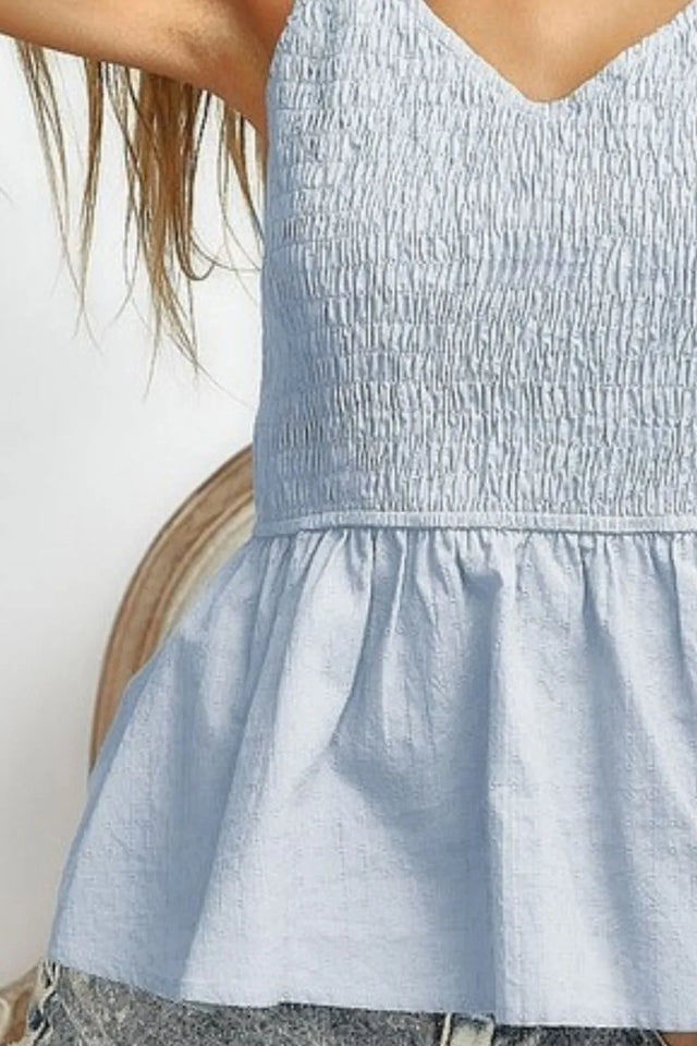 Eyelet woven sleeveless elasticized top with peplum and smocked details.