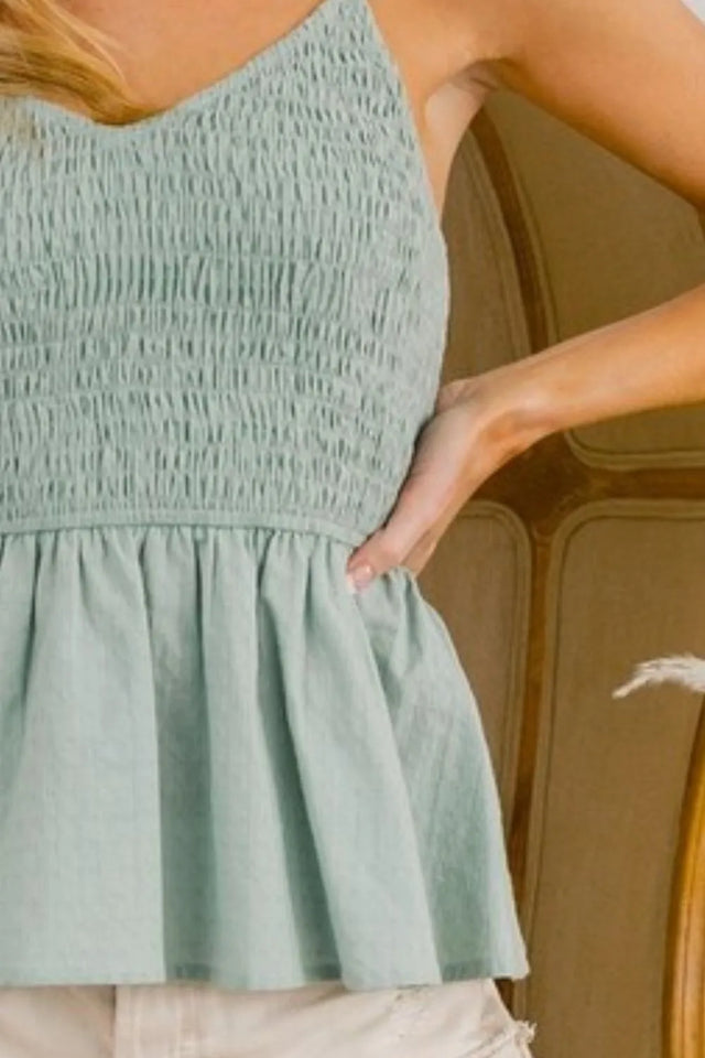 Eyelet woven sleeveless elasticized top with peplum and smocked details.