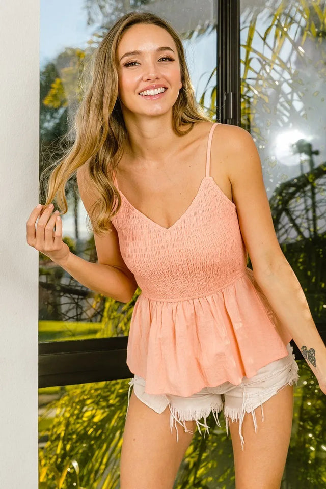Eyelet woven sleeveless elasticized top with peplum and smocked details.