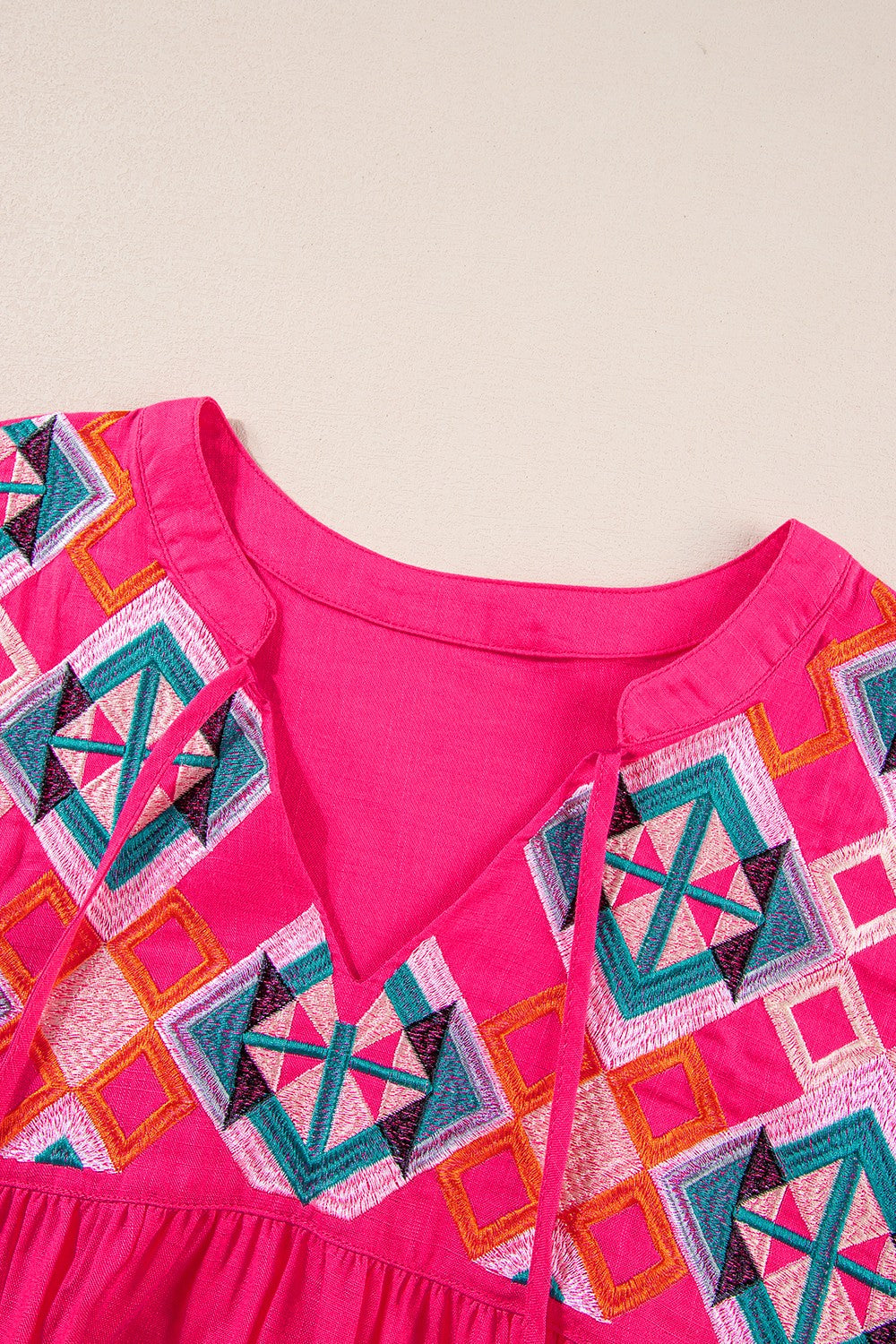 Geometric embroidered tassel tie neck blouse.