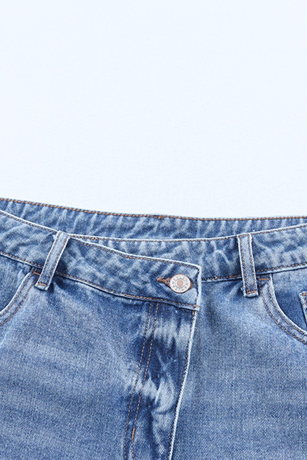 High rise crossover waist denim shorts with buttons, distressed details, and raw hem.
