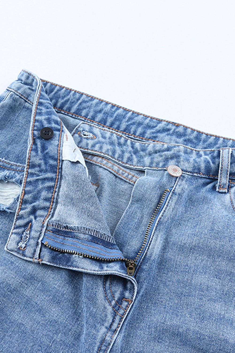 High rise crossover waist denim shorts with buttons, distressed details, and raw hem.