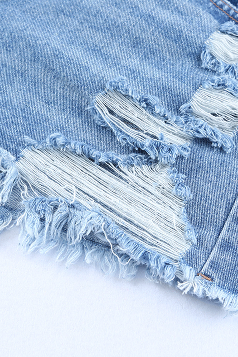High rise crossover waist denim shorts with buttons, distressed details, and raw hem.