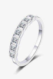 A minimalist silver moissanite half-eternity ring features a slim rhodium-plated band with seven square stones in raised bezel settings.