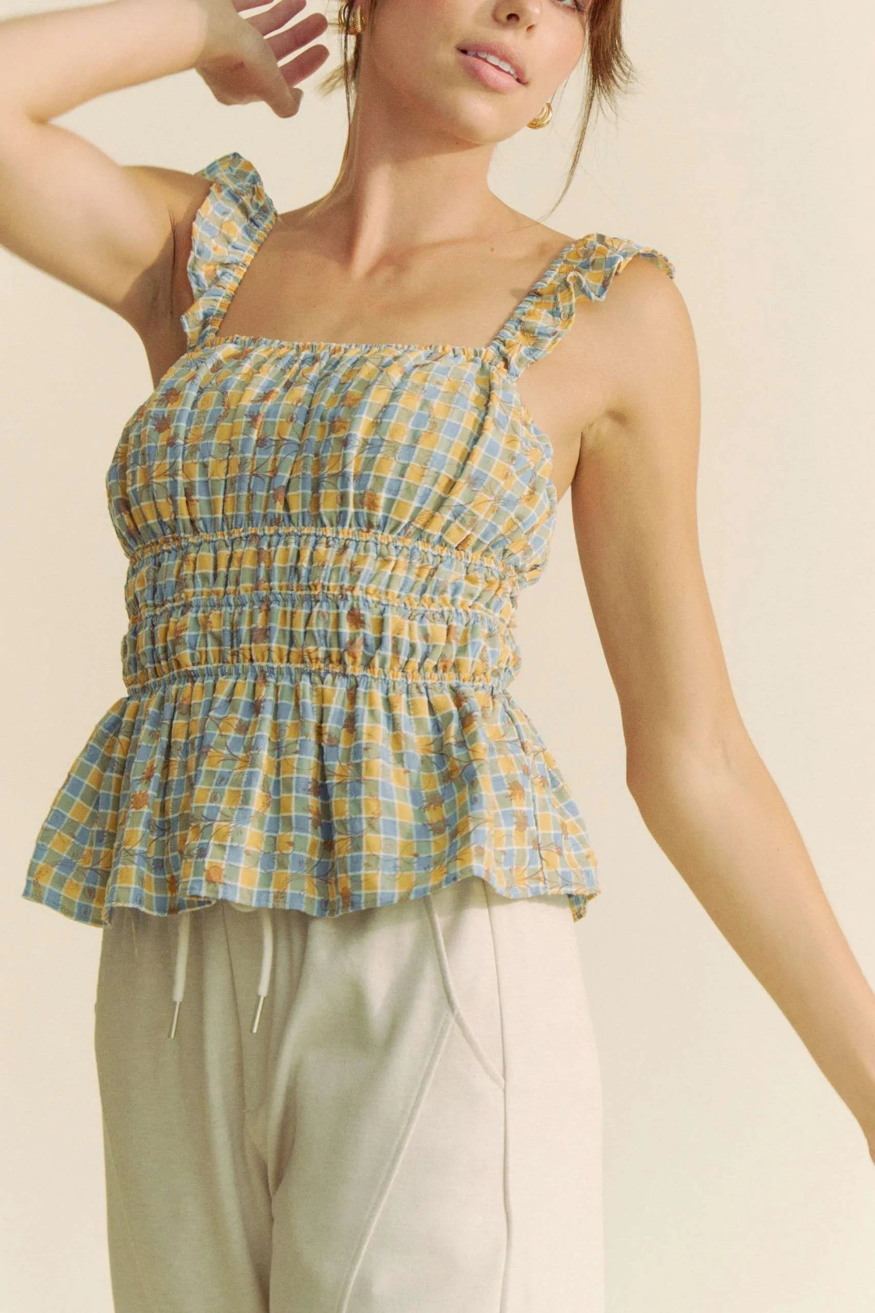 Plaid ruffled strap smocked sleeveless top with peplum, ruched details, and moderate stretch.