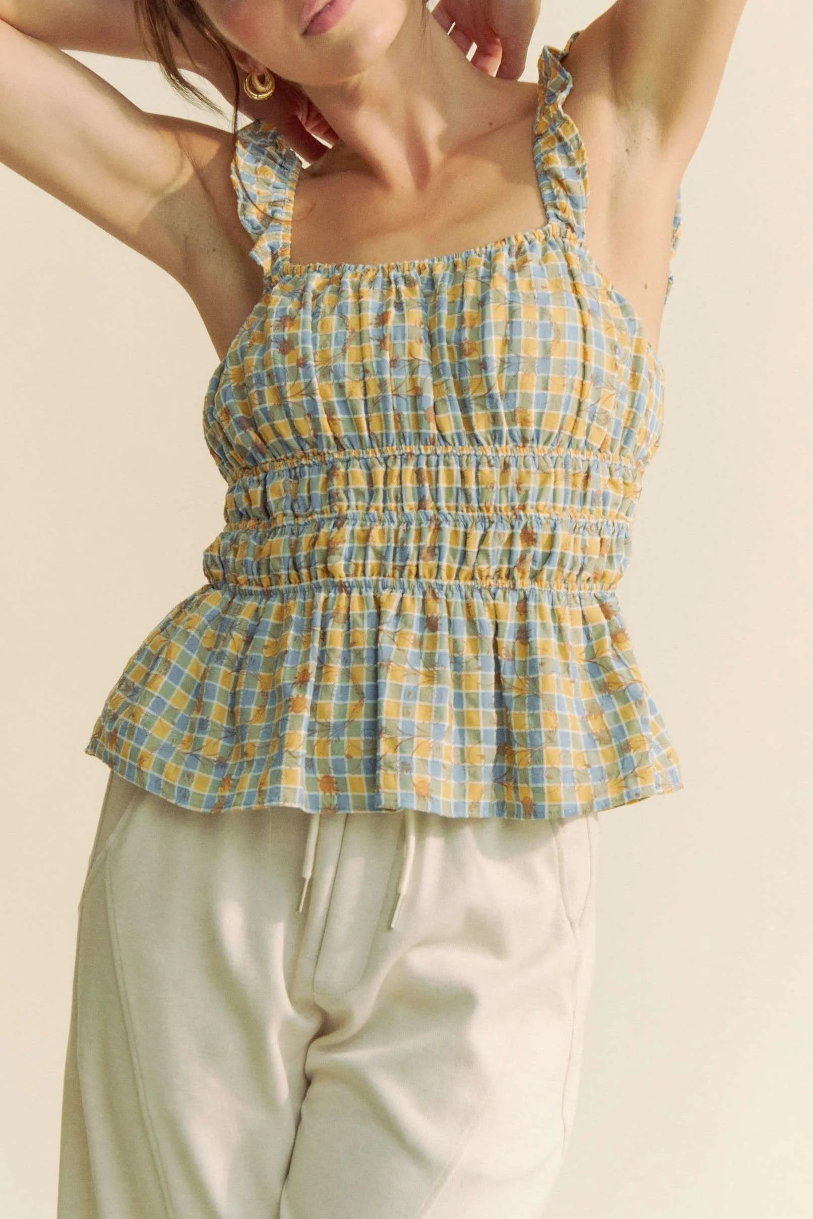 Plaid ruffled strap smocked sleeveless top with peplum, ruched details, and moderate stretch.