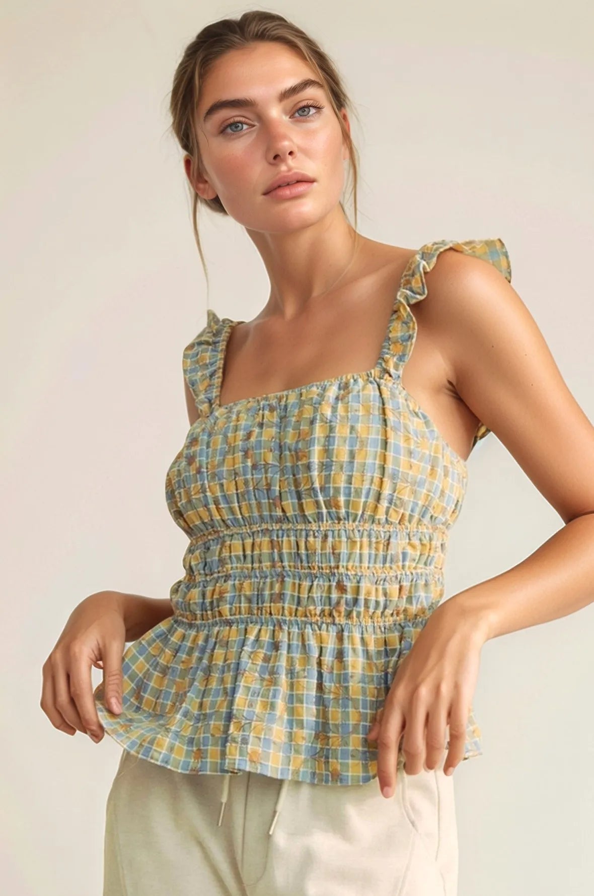 Plaid ruffled strap smocked sleeveless top with peplum, ruched details, and moderate stretch.
