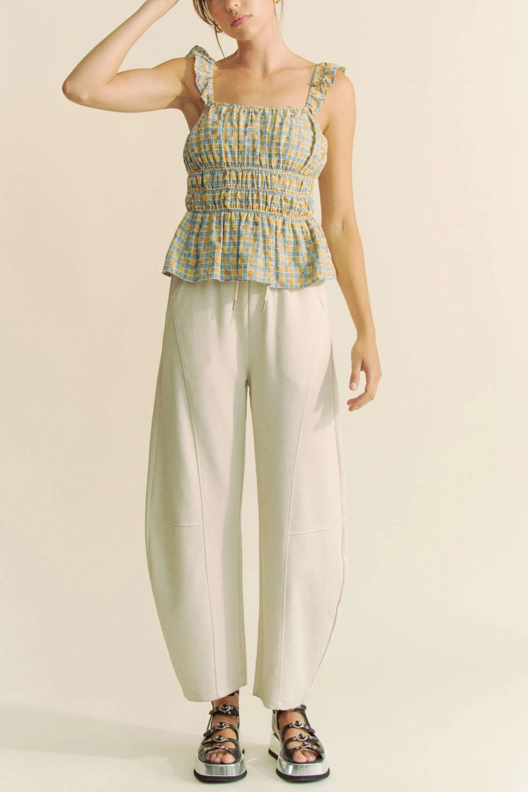 Plaid ruffled strap smocked sleeveless top with peplum, ruched details, and moderate stretch.