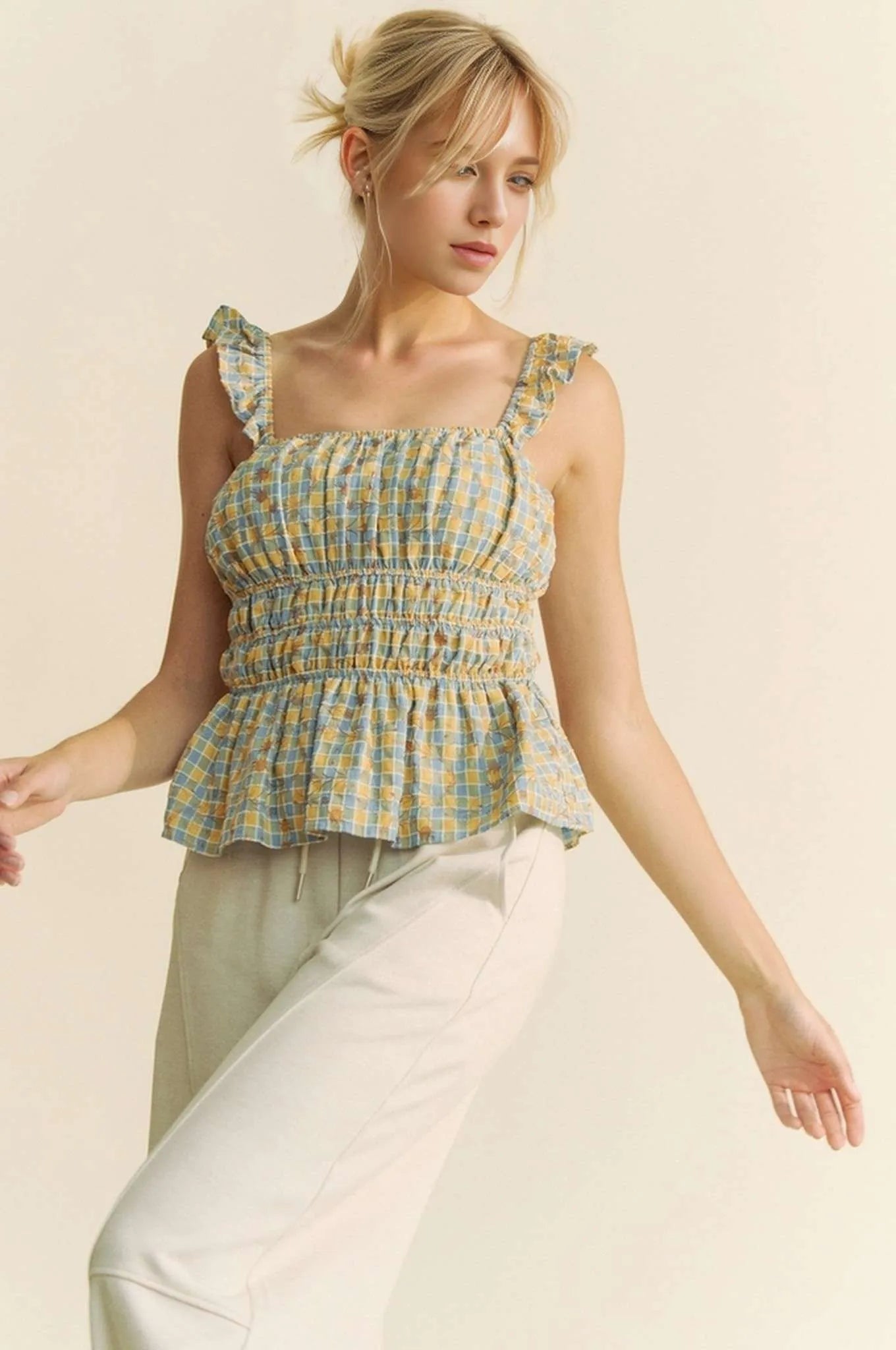 Plaid ruffled strap smocked sleeveless top with peplum, ruched details, and moderate stretch.