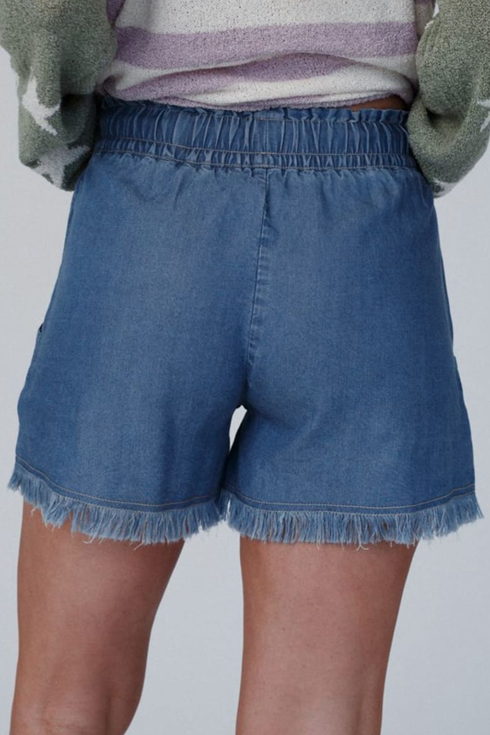 Distressed raw hem denim shorts with buttons and pockets.