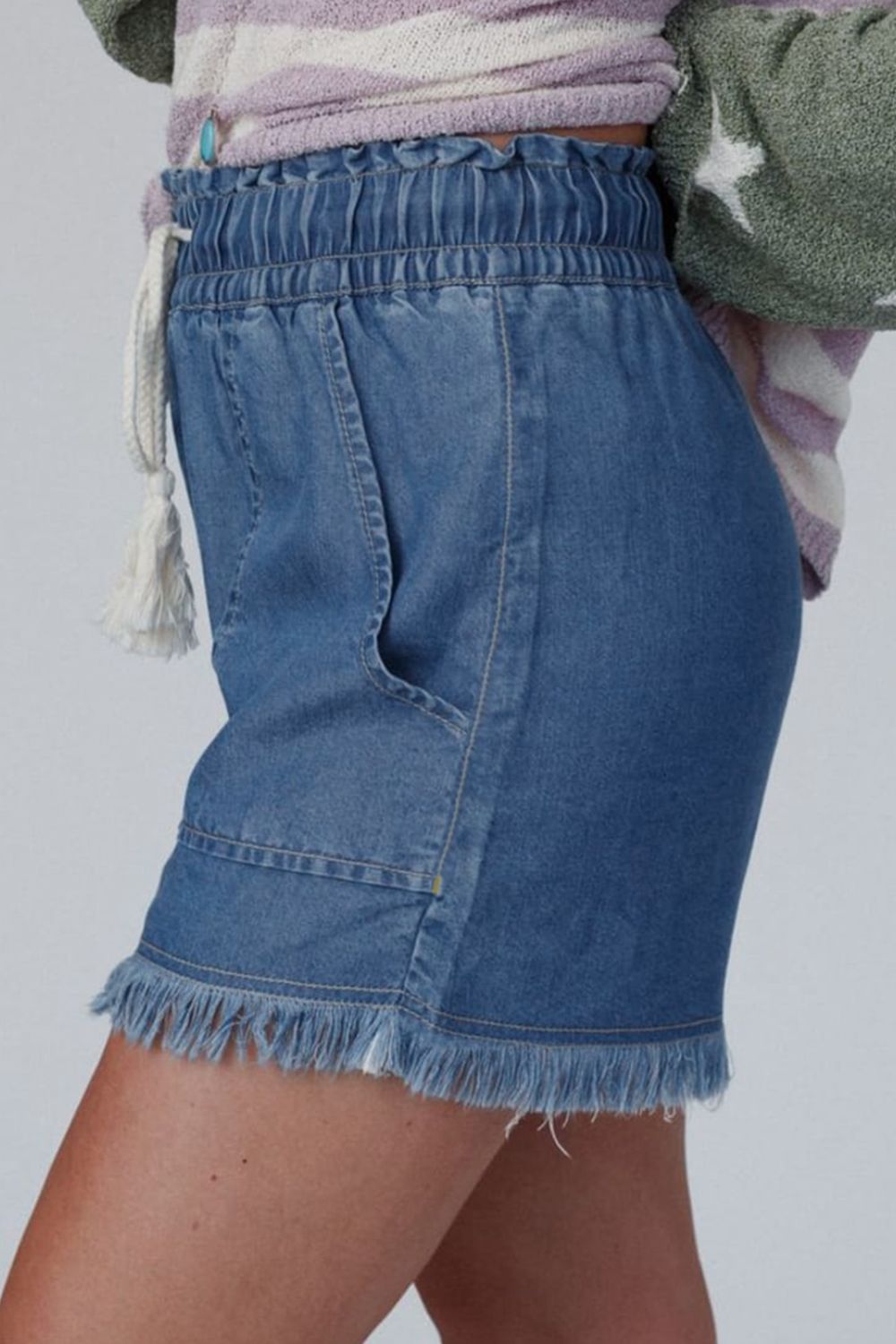 Distressed raw hem denim shorts with buttons and pockets.