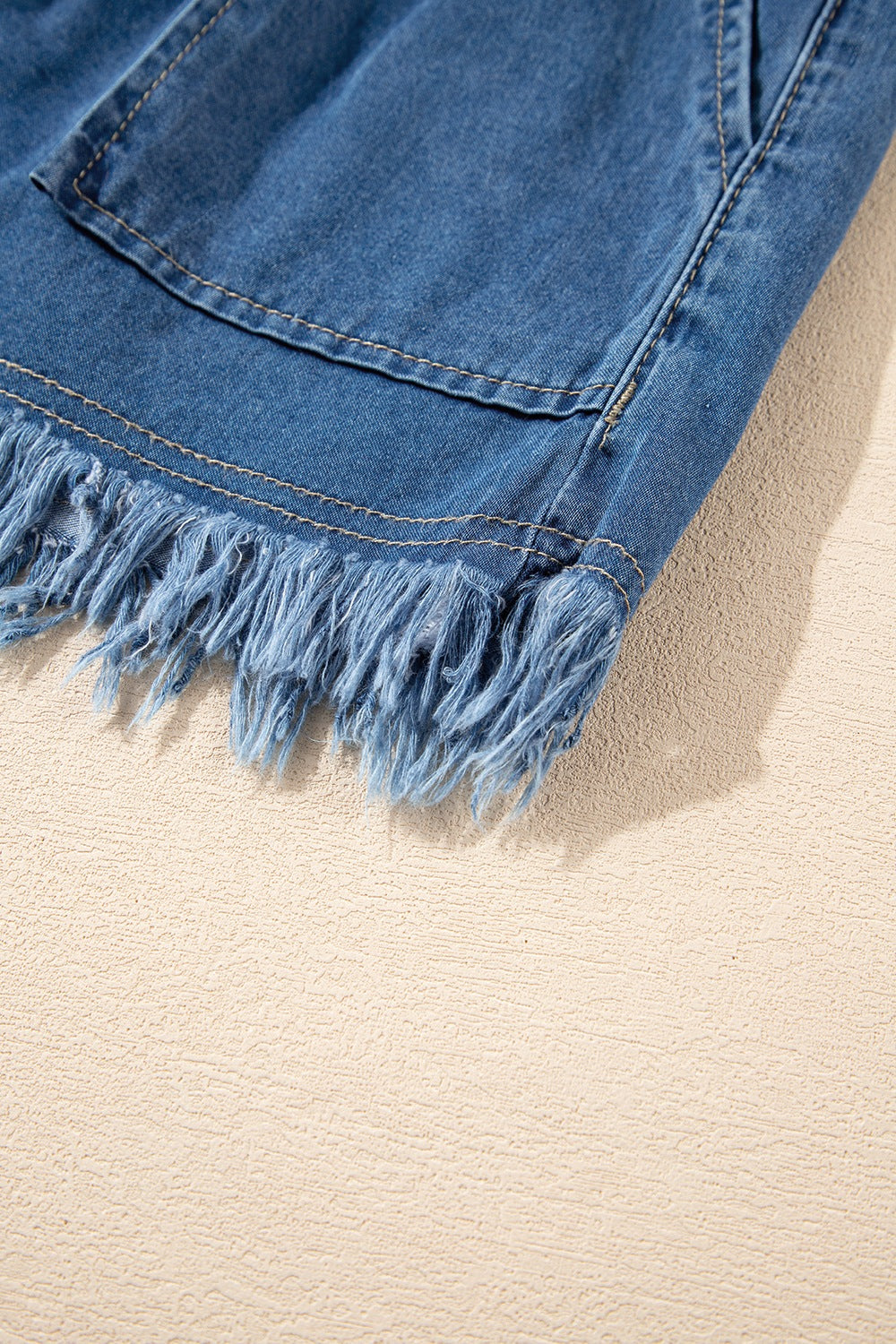 Distressed raw hem denim shorts with buttons and pockets.