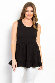 Ruffled sleeveless babydoll top with peplum and ruched details, opaque and slightly stretchy.