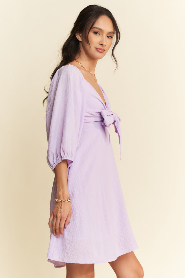 Woman wearing a light purple dress with a plain background
