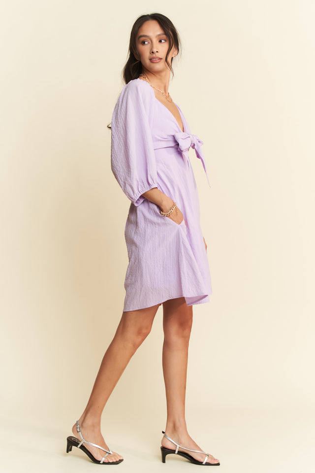 Woman wearing a light purple dress with a plain background