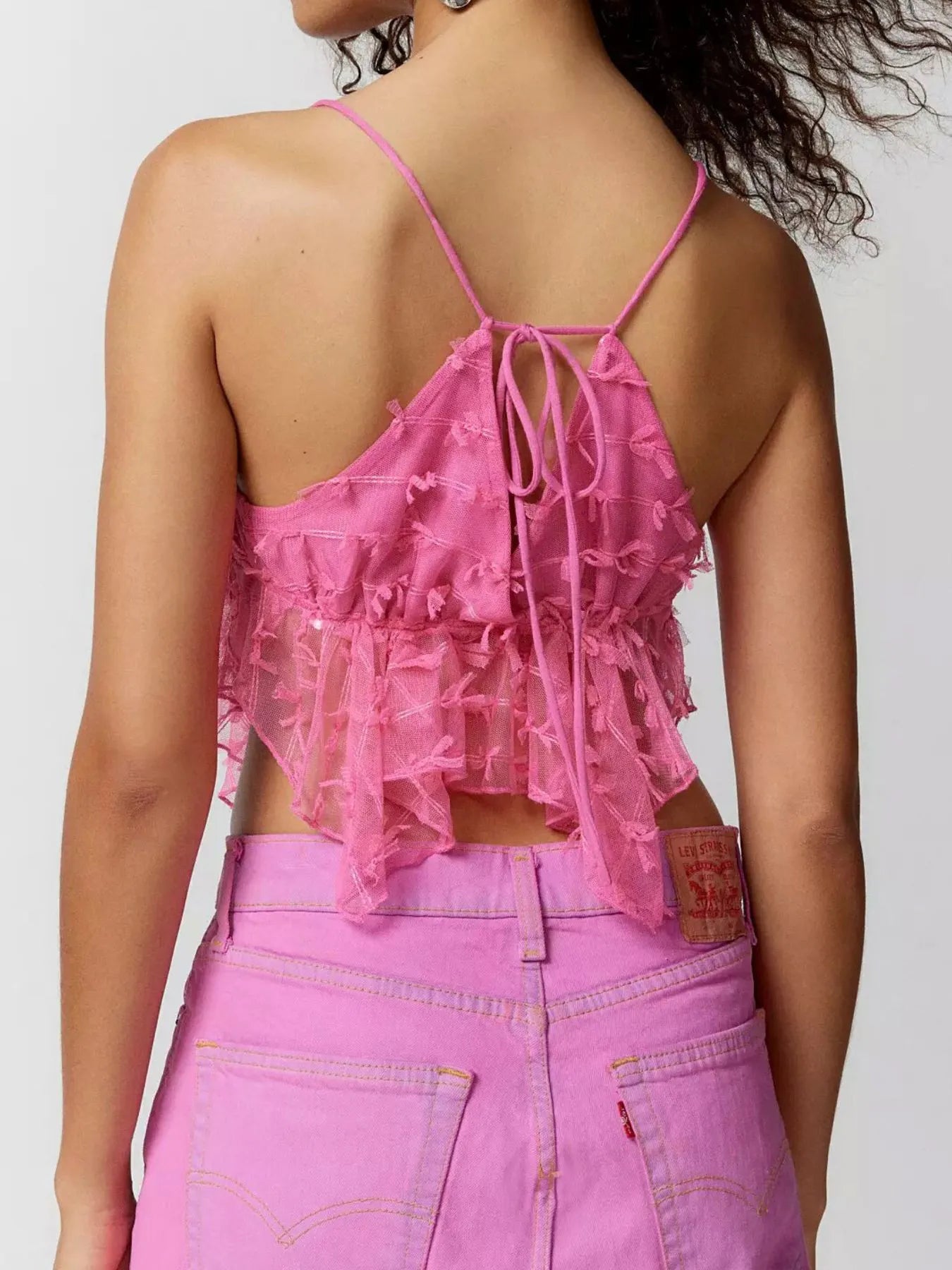 Sheer lace cami top with delicate trim and tie detail.