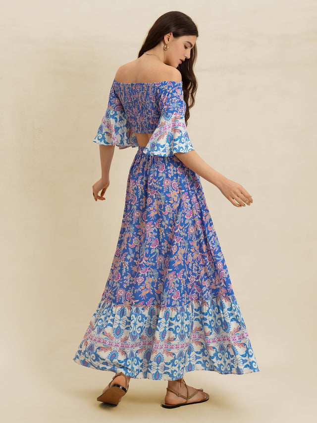 Woman wearing a blue floral off-shoulder top and long skirt on a beige background