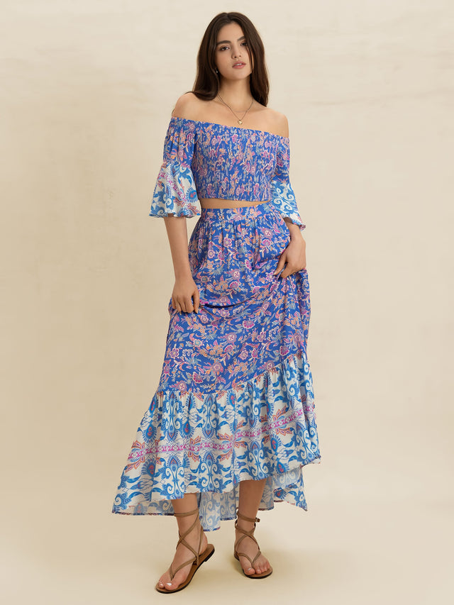 Woman wearing a blue floral off-shoulder top and skirt set on a beige background