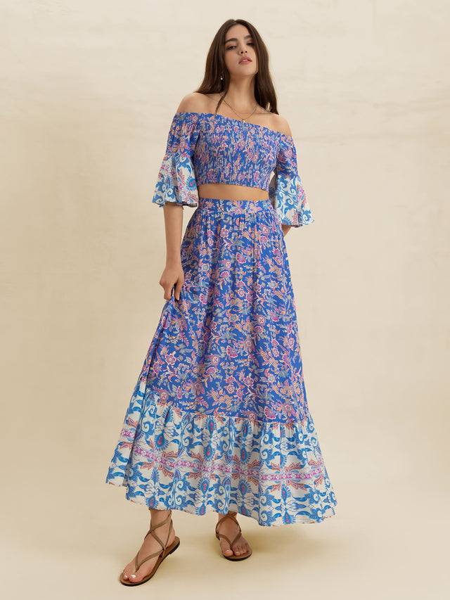 Woman wearing a blue floral off-shoulder top and skirt set on a beige background
