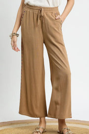 Wide leg drawstring pants with pockets and decorative trim.