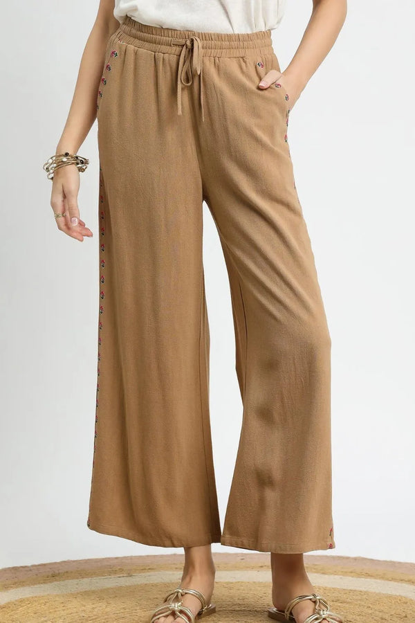Wide leg drawstring pants with pockets and decorative trim.