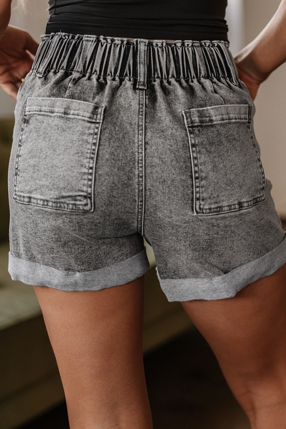 Distressed raw hem denim shorts with buttons and pockets.
