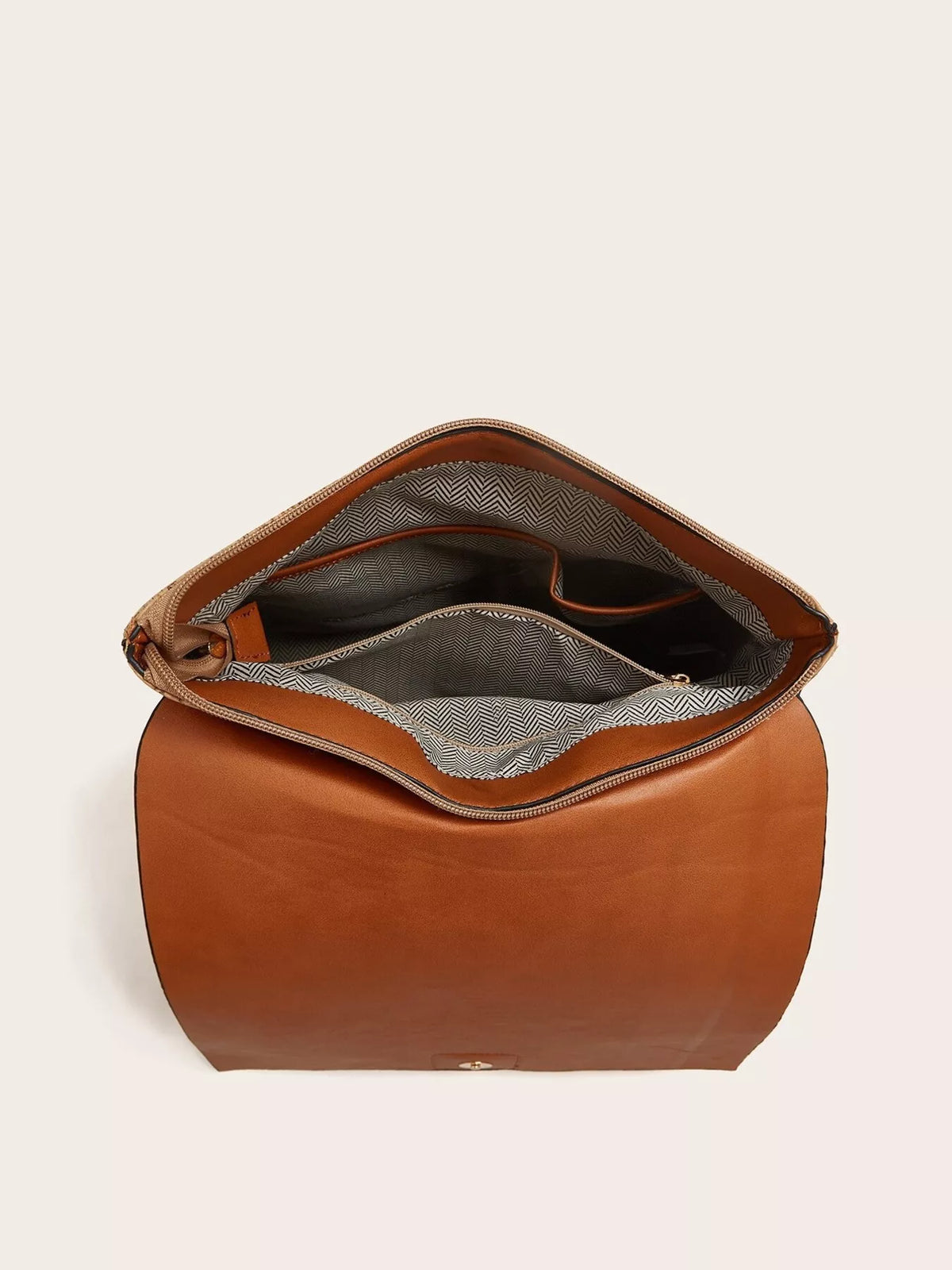 Open medium brown PU leather backpack showing its spacious interior, zippered compartments, and contrasting chevron-patterned lining.