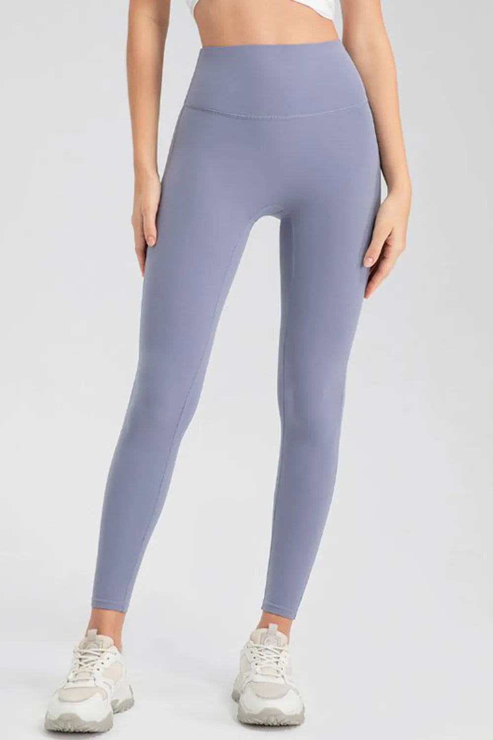 Model wearing lavender high-waist skinny active leggings with a smooth fitted silhouette, ankle-length cut, and visible horizontal waistband seam.