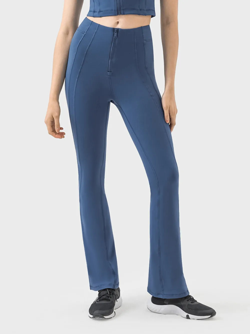 Model wearing navy blue high-waist active pants with a front zipper, curved seam details, slim straight-leg silhouette, and slight stretch.