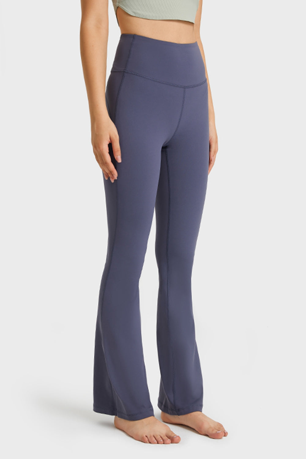Model stands barefoot wearing solid navy elastic-waist flare yoga pants with a high-rise waistband, fitted legs, visible seams, and flared hems.