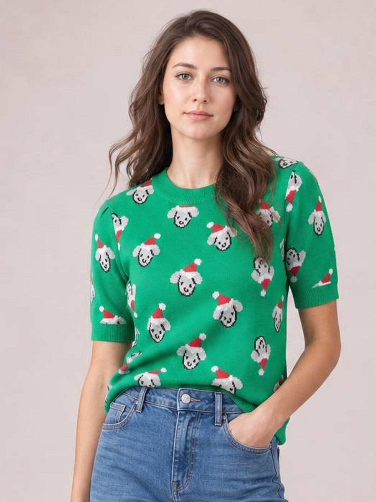 A model wears a green round-neck short-sleeve sweater with an abstract Christmas dog pattern, ribbed neckline and cuffs, and a relaxed silhouette.