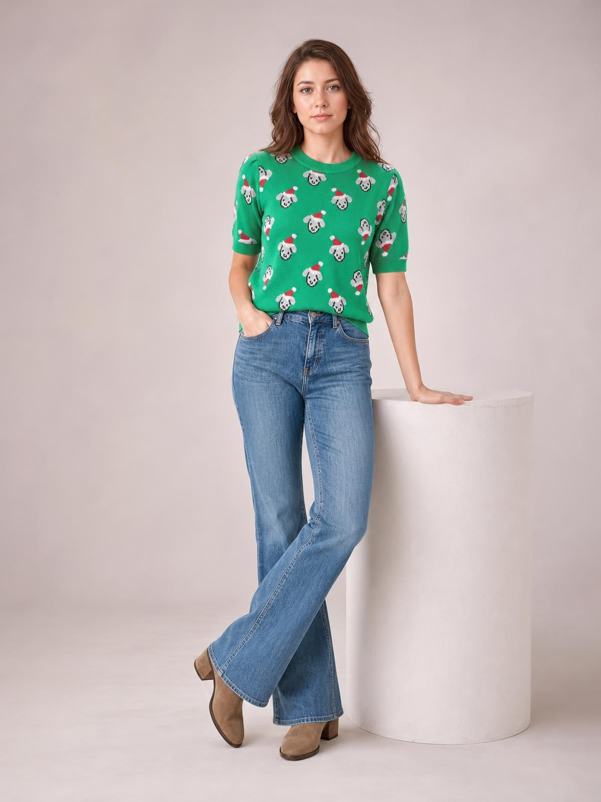 Model wears a green Christmas short-sleeve sweater with a round neck and abstract dog pattern, shown in a relaxed pose with one hand in her pocket.