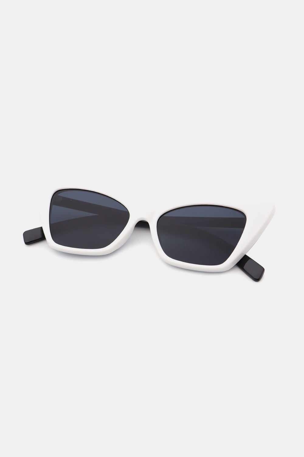 White cat-eye sunglasses feature sculpted polycarbonate frames, dark acetate lenses, and contrasting black temples for a bold retro silhouette.