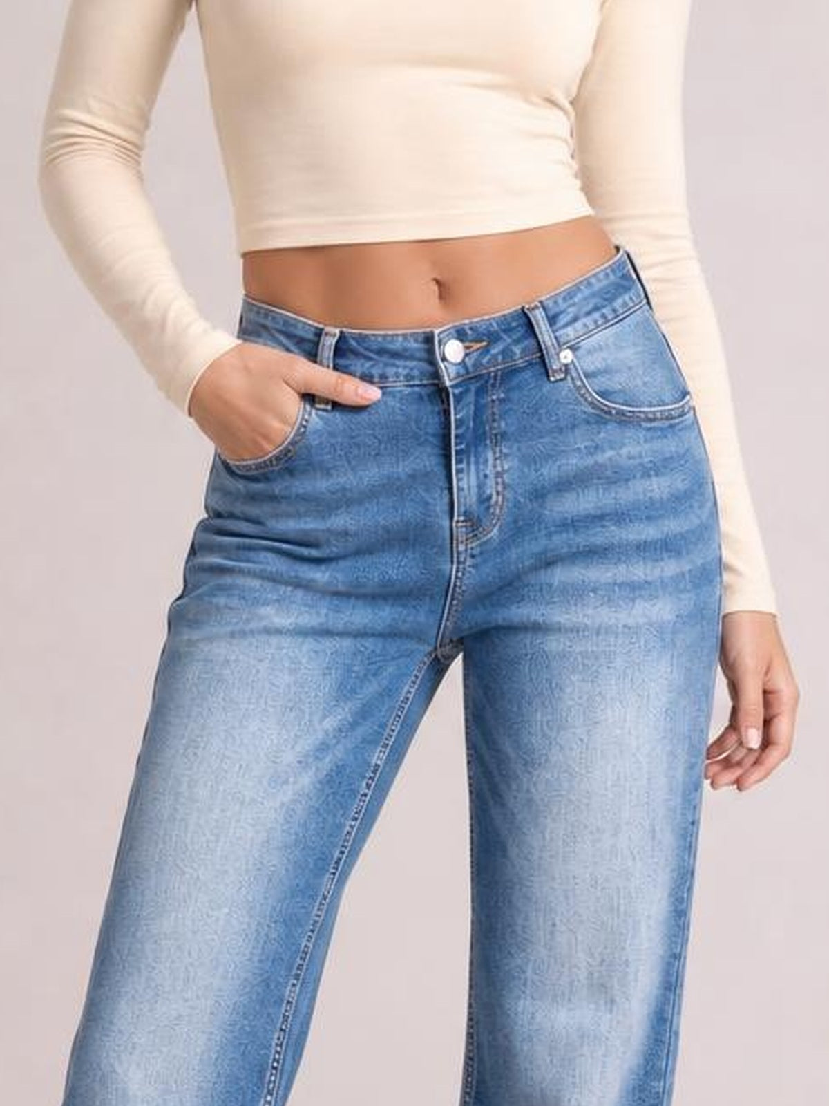 Model wearing light blue acid-washed straight-leg full-length jeans with front pockets, belt loops, button closure, and visible seam construction.