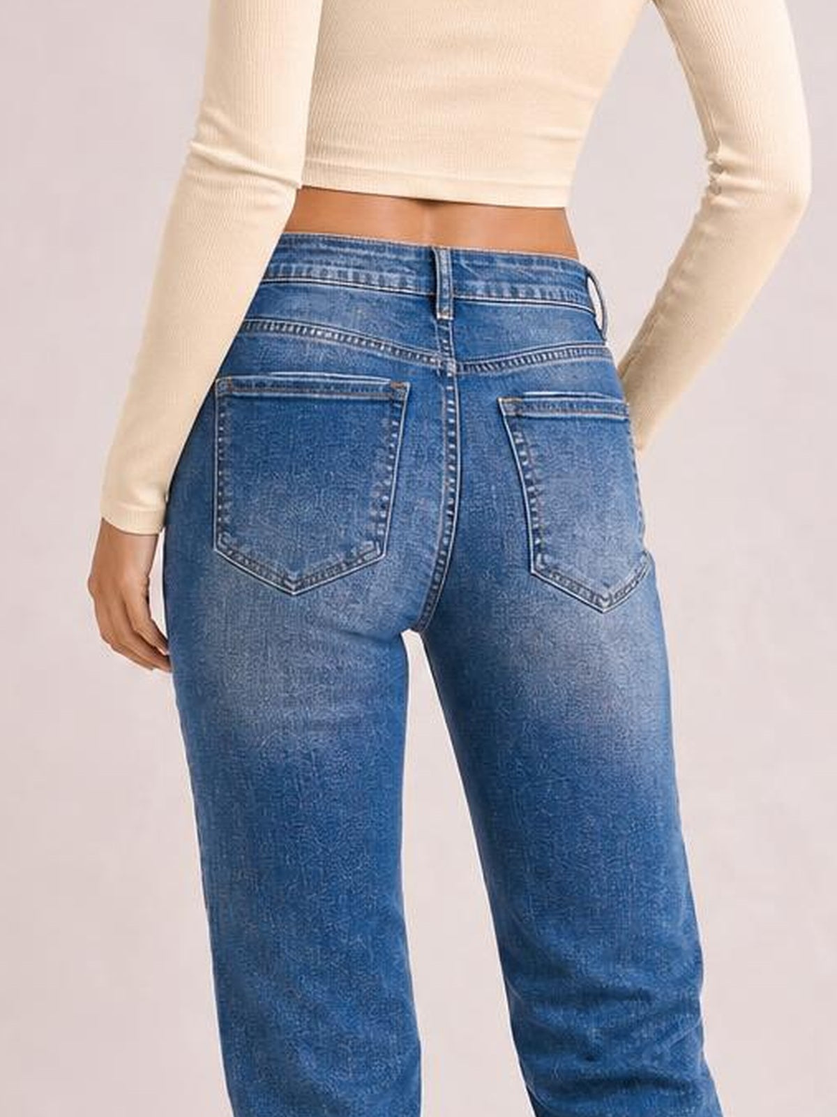 A model shown from behind wears blue acid washed straight-leg full-length jeans with a structured waistband, belt loops, contrast stitching, and two back pockets.
