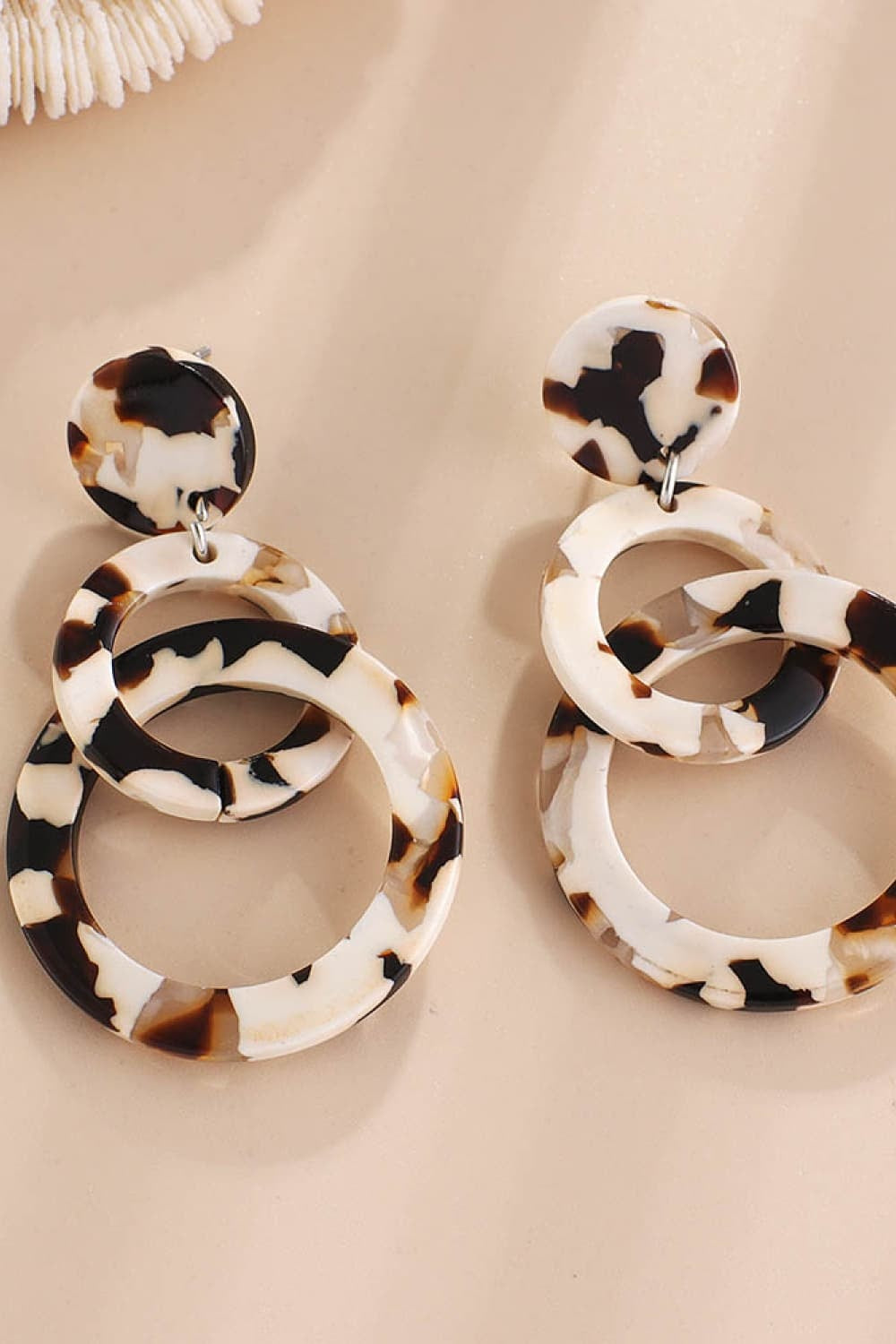 Acrylic Double-Hoop Earrings feature polished, tortoiseshell-patterned circular hoops layered beneath matching round stud tops for a sculptural statement silhouette.