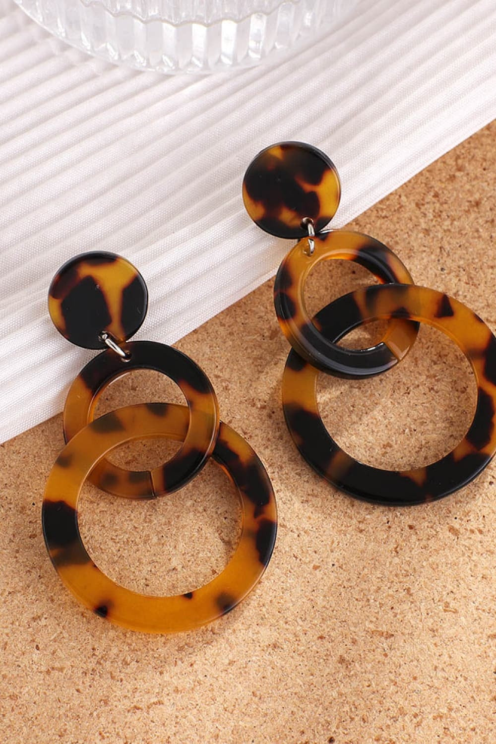 Acrylic double-hoop earrings in a tortoiseshell pattern feature round tops and layered circular hoops for a bold, sculptural statement silhouette.