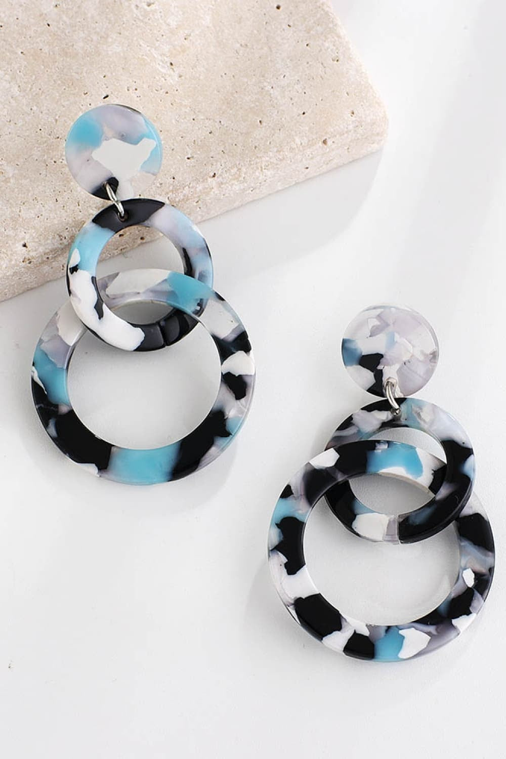 Acrylic double-hoop earrings feature layered round hoops with black, white, and blue marbled coloring and matching circular stud tops.