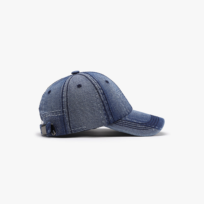 Blue cotton adjustable baseball cap shown in profile with a structured six-panel crown, curved brim, visible seam detailing, ventilation eyelets, and back strap.
